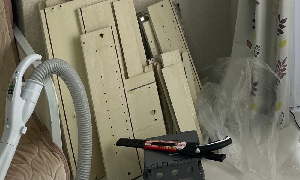 解体されたドレッサーの木片とノコギリと掃除機。